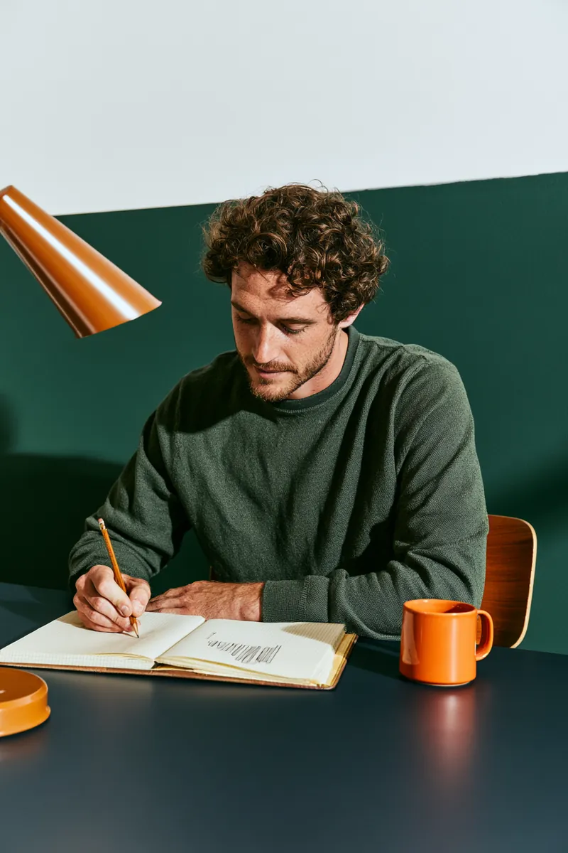 American man sketching a personal loan payment bar chart in a graph-paper notebook