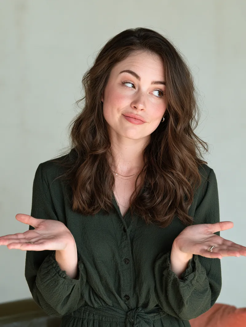American woman with a playful questioning gesture against a plain studio wall
