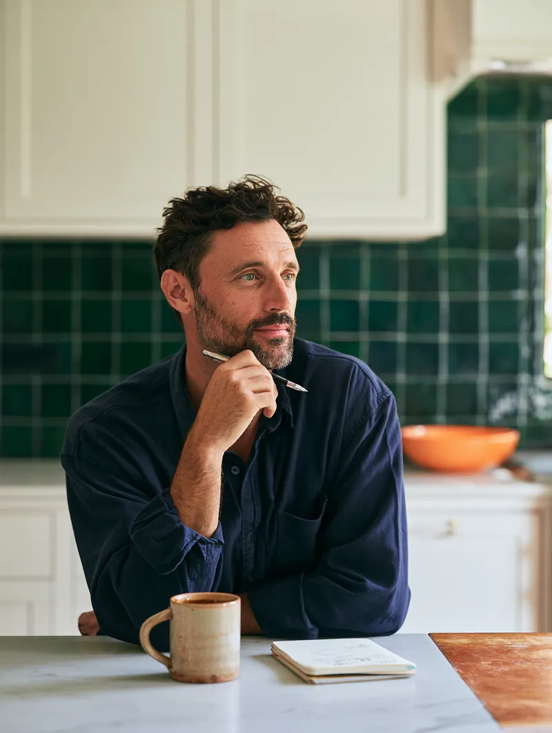 American man at a kitchen island working through consolidation math in a budget notebook